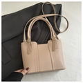Detalle del bolso tote beige mostrando la textura y costuras elegantes en el cuero - Caqui