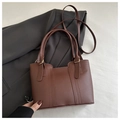 Detalle de bolso tote de cuero mate marrón oscuro con correa ajustable y herrajes dorados - Marrón