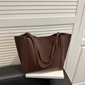 Grande borsa tote vintage in pelle opaca color caffè appoggiata su un libro con sfondo - Marrone