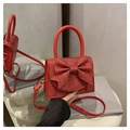 Détail d'une pochette à paillettes rouges avec nœud et finitions dorées sur présentoir - Rouge