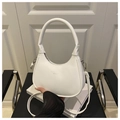 Detalle de bolso medialuna blanco con texto Fashion & Bags en un sillón negro - Blanco