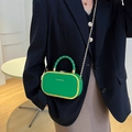 Sac à main en cuir vert avec cadre doré et bandoulière sur une veste de costume - Vert