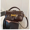 Close-up of dark brown oily leather handbag with polished gold-tone metal buckle - Coffee