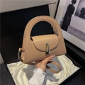 Minimalist beige handbag featuring a unique curved handle and gold geometric buckle lock - Khaki