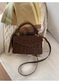 Detail einer dunkelbraunen Handtasche mit Leopardenmuster auf einem cremefarbenen Sofa - Braun