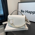 Fashionable white leather square crossbody bag with gold chain strap on a book - White