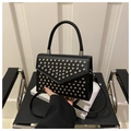 Detailaufnahme einer schwarzen Handtasche im Punk-Stil mit Silbernieten und Rundgriff - Schwarz