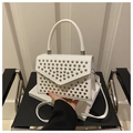 Detail einer weißen Lederhandtasche mit silbernen Metallnieten und strukturiertem Griff - Weiß