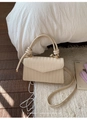 Close-up of V-shaped weave texture and knotted handle on a cream crossbody bag - White