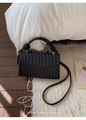 Close-up of black woven square bag with sophisticated V-shaped texture on white rug - Black