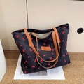 Grande borsa tote nera con stampa ciliegie e manici in pelle marrone su sfondo bianco - Nero
