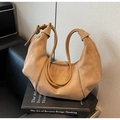 Détail du sac hobo avec bandoulière nouée posé sur un livre dans un décor minimaliste - Khaki