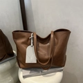 Bolso tote minimalista de cuero marrón oscuro con colgante de contraste en fondo gris - Marrón