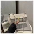 Detail einer beigen Baguette-Tasche mit Krokoprägung und goldenem Drehverschluss - Khaki