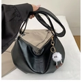 Close-up of black leather underarm bag with gold zipper and a cute white monster charm - Black with Pendant
