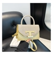 Detailansicht der cremefarbenen Ledertasche mit goldenem T-Logo und glitzernder Klappe - Gold