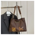 Dettaglio della borsa tote marrone scuro con texture opaca retrò e toppe grafiche - Marrone