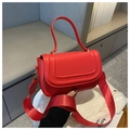 Detailed shot of red saddle bag featuring golden hardware and wide fabric strap - Red