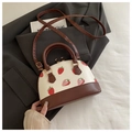 Detail der Umhängetasche mit Erdbeerdruck und goldenen Beschlägen auf grauem Stoff - Kaffeebraun