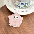 Support de téléphone en forme d'étoile rose avec smiley et coutures sur table - Rose Clair