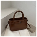 Detail of dark brown bucket bag featuring silver buckle and round top handle - Tan