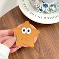 Détail du support téléphone étoile jaune avec de grands yeux blancs et motif Smile - Brun doré