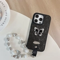 Macro view of black crinkled texture phone case with rhinestone butterfly and pearl strap - Large Hole Pearl Pattern - Silver Butterfly Logo - White Pearl Chain - Black / iPhone 17 Pro Max