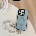 Macro shot of light blue ruched leather iPhone case with rhinestone butterfly and beaded charm - Large Hole Pearl Pattern - Silver Butterfly Logo - White Pearl Chain - Blue / iPhone 17 Pro Max