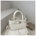 Detail einer minimalistischen beigen PU-Beuteltasche mit Metallschnalle auf Steinstufen - Weiß