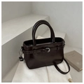 Detail view of a dark coffee patent leather bucket bag with silver buckle and top handle - Black