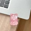 Detail view of pink glitter bear phone grip on a silver laptop and wooden table surface - Adhesive Pop Grip Glitter Bear-Red
