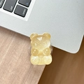 Close-up of translucent yellow gummy bear phone grip on a laptop and desk surface - Adhesive Pop Grip Glitter Bear-Yellow