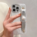 Elegant iPhone case with pearl texture, silver flower relief, and functional wrist strap - Camellia Pearl Wristband / iPhone 17 Pro Max