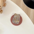 Detail of glittery bear phone stand with golden stars in transparent resin on white desk - Magnetic Model / Brown