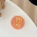 Detail eines orangefarbenen Glitzerteddy-Handyhalters mit goldenen Sternpailletten - Magnetisches Modell / Orange