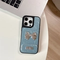 Detail of light blue wrinkled leather phone case with silver metallic bow and min logo - Large-hole Pearlescent Texture - Matching Mirror Stand - Mini Bow - Blue / iPhone 17 Pro Max