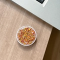Close-up of a round glitter phone socket with gold star sequins on a wooden desk - Colorful Sequins No.15
