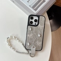 Détail de la coque iPhone argentée avec nœuds pailletés et bracelet en perles - Argent