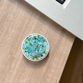 Detail of round phone socket with blue sequins on a wooden desk with laptop - Colorful Sequins No.3