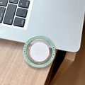 Macro detail of round MagSafe phone grip in light green with Gift For You text on desk - Dark Green