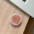 Detailed top view of a round pink glitter phone socket with star sequins on a wooden desk - Colorful Sequins No.12