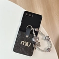 Vue détaillée de la coque en cuir avec lettres miu dorées et dragonne en perles argentées - Noir / Samsung ZFlip3