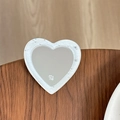 Gros plan d'un miroir cœur pailleté avec logo mine sur une surface en bois texturé - Blanc