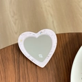 Détail macro du support miroir en cœur avec cadre pailleté violet et logo gravé - Rose