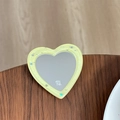 Macro view of heart-shaped glitter phone grip mirror with star sequins on wooden table - Yellow