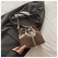 Detail of a brown bucket bag with shiny patent leather texture and silver chain drawstring - Coffee