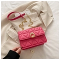 Detail of rose pink quilted crossbody bag with gold horseshoe buckle on white suit - Pink