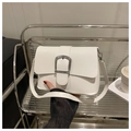 Detail einer weißen Umhängetasche mit großer silberner Metallschnalle als Verschluss - Weiß