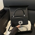 Schwarze Lackleder-Handtasche mit silberner G-Schnalle auf einer schwarzen Geschenkbox - Schwarz