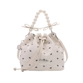 White bucket bag with black bow prints, pearl handle, and drawstring closure for women - White Bow